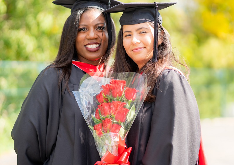 two students smiling with flowers