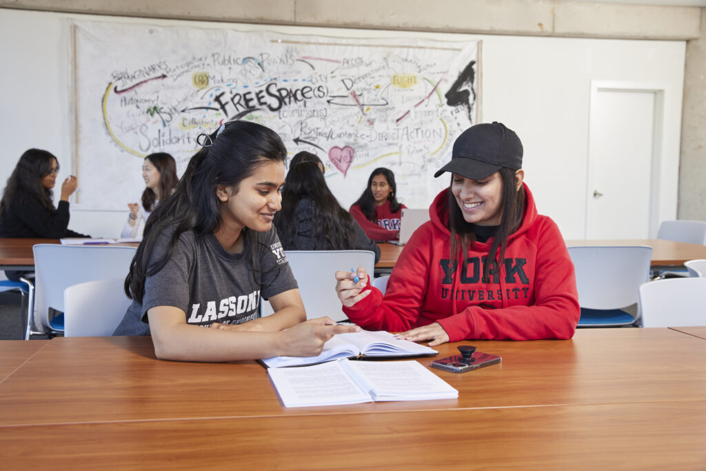 two students sitting together and writing in one notebook