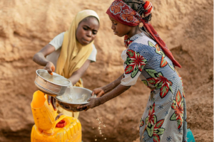 Two young girls are collecting water